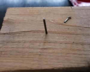 A finishing nail works as a holder for the dolls.